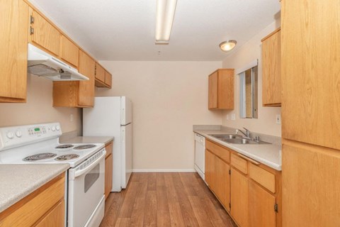 A kitchen with wooden cabinets and a white stove top oven.