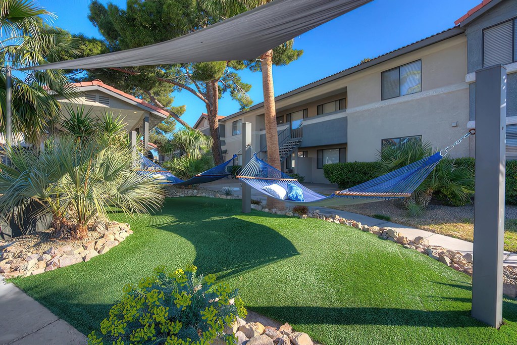 a yard with two hammocks in front of a building