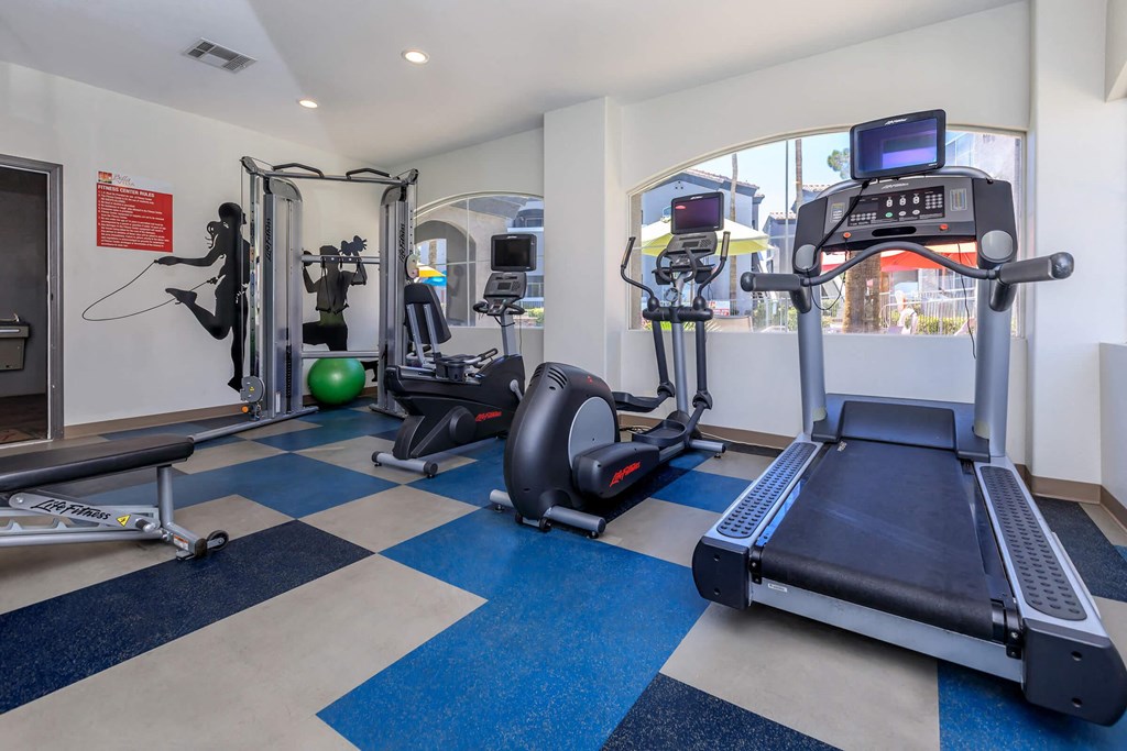 a gym with treadmills and other exercise equipment in a room with a window