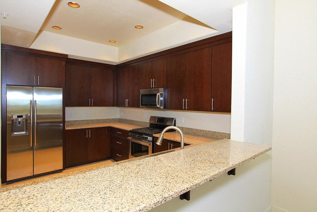 a kitchen with a granite counter top and a stainless steel refrigerator
