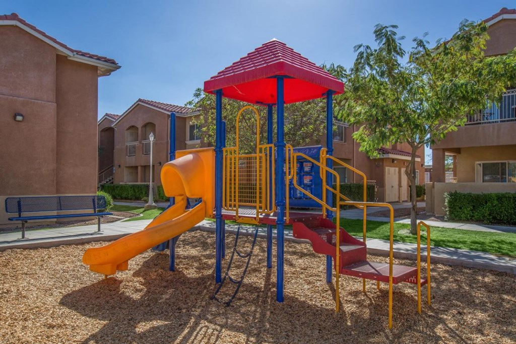 A playground with a red and yellow slide and a red and blue canopy.