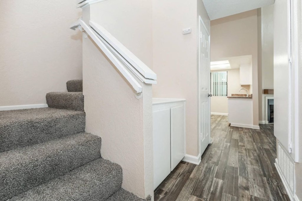 a gray carpeted staircase leading to a hallway with a white door