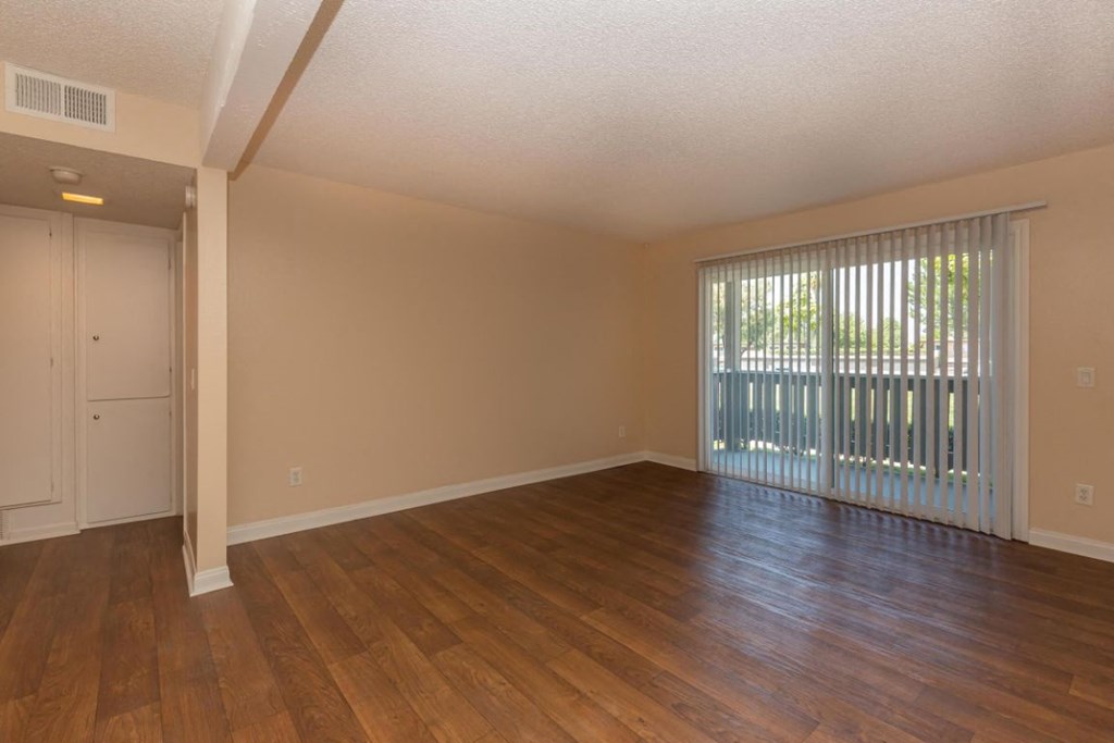 an empty living room with wood floors and a sliding glass door