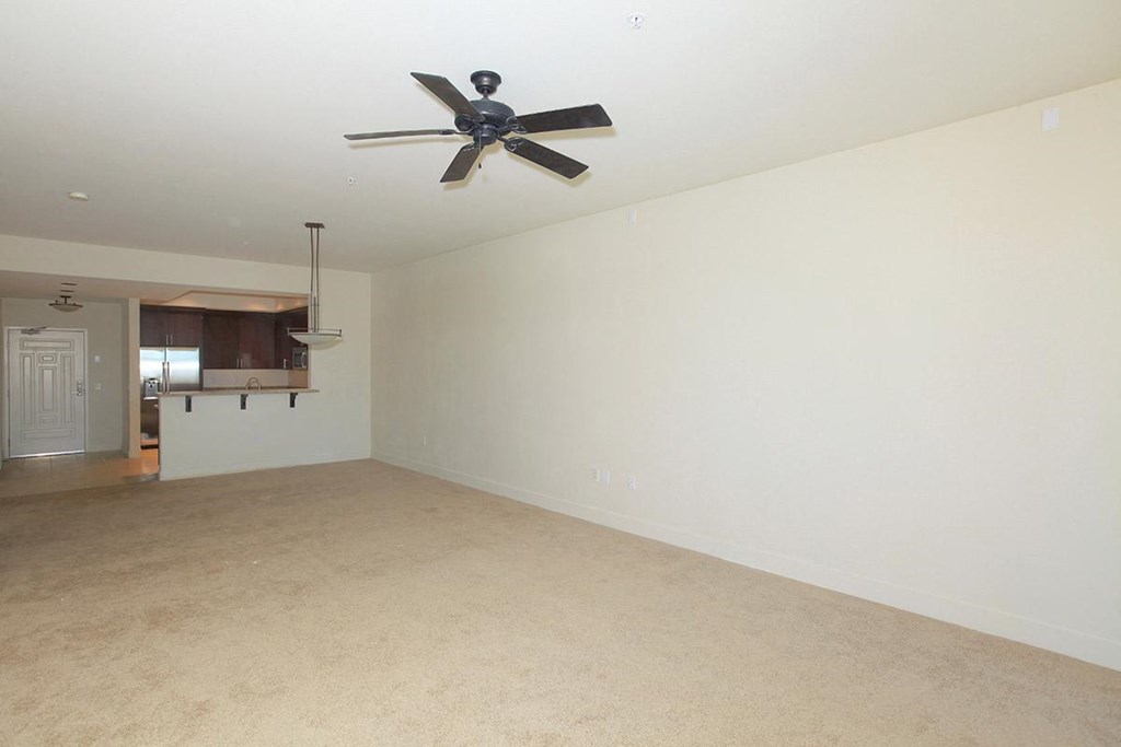 an empty living room with a ceiling fan