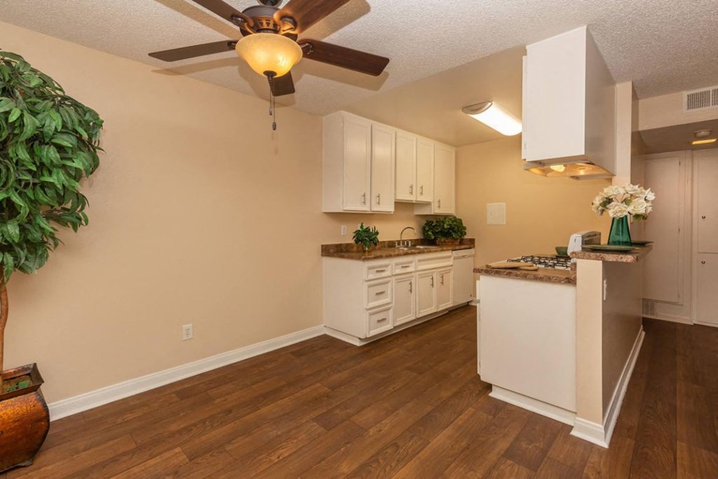 a kitchen with white cabinets and a ceiling fan