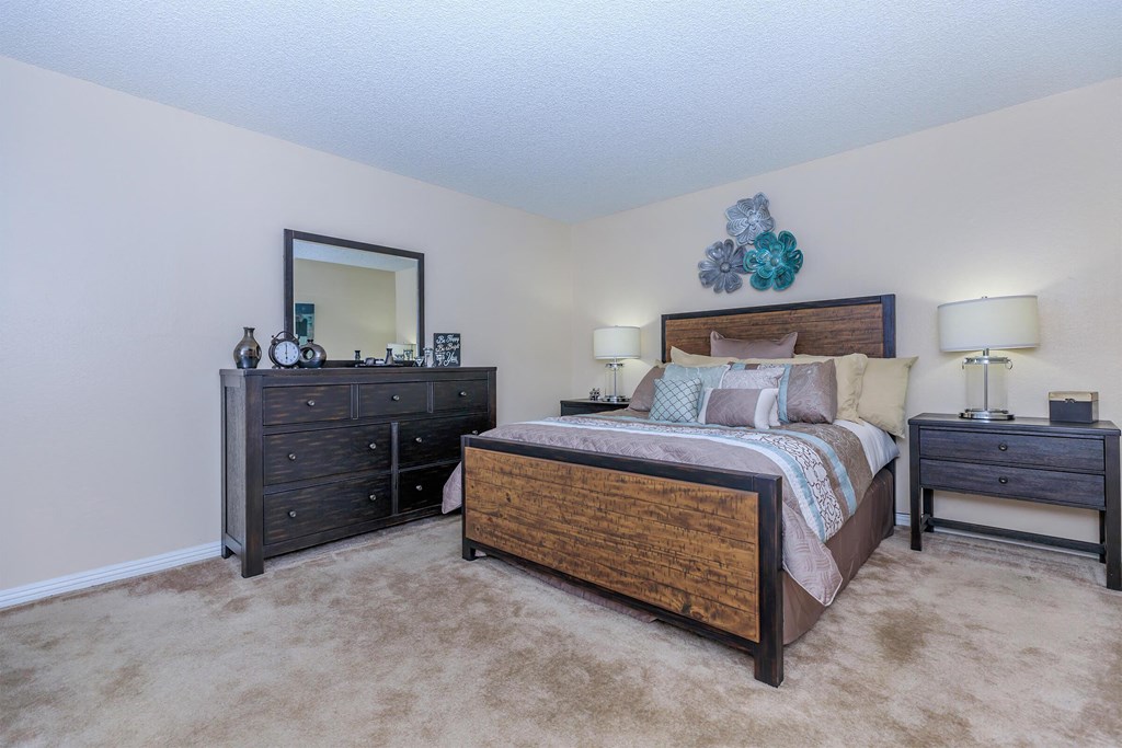 a bedroom with a bed and dressers and a mirror