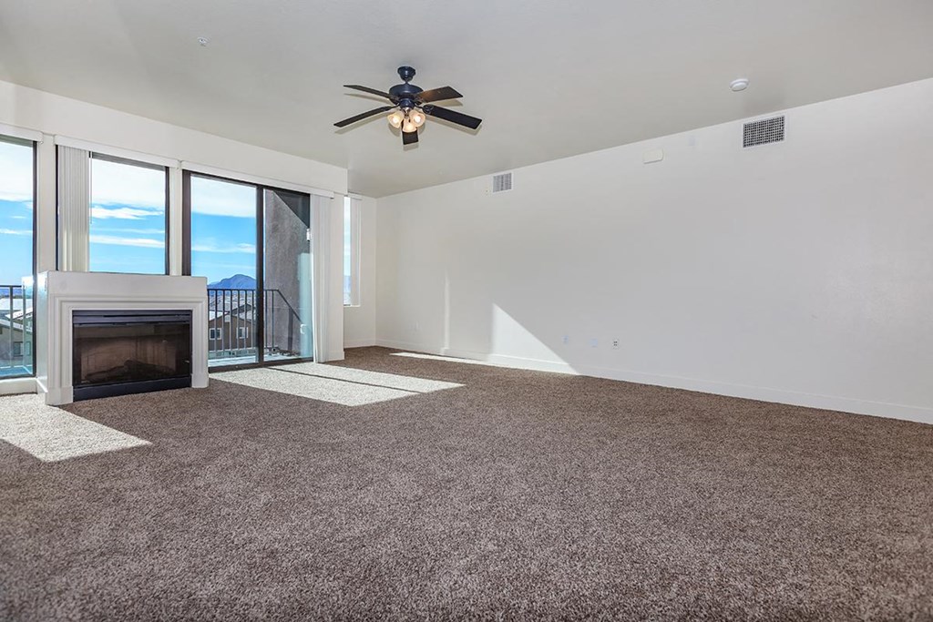 an empty living room with a ceiling fan and a fireplace