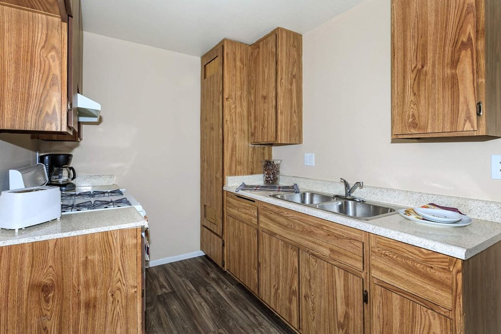 A kitchen with wooden cabinets and a white toaster on the counter.