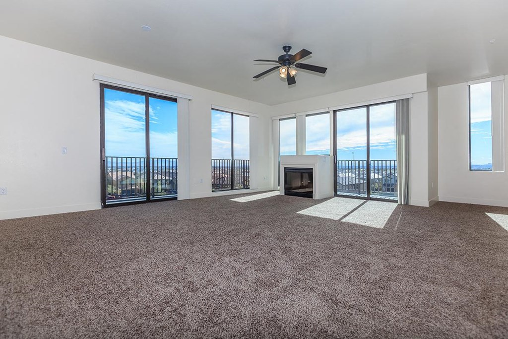 an empty living room with a ceiling fan and a fireplace