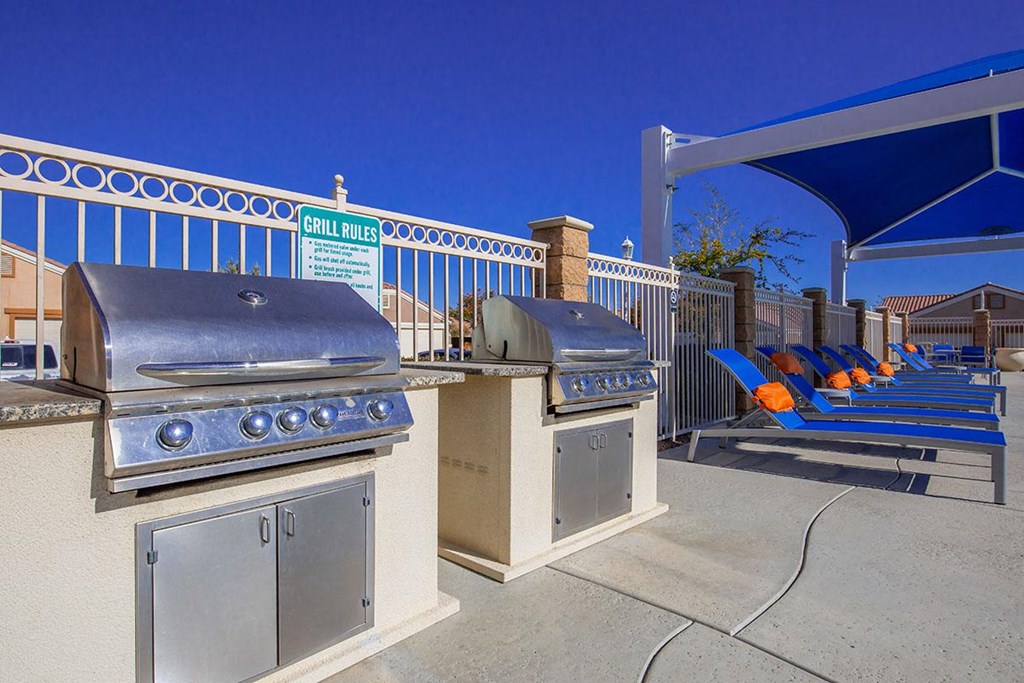 two bbq grills and picnic benches at a park