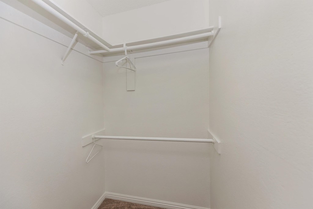 a walk in closet with white walls and a white hanger rack on the wall