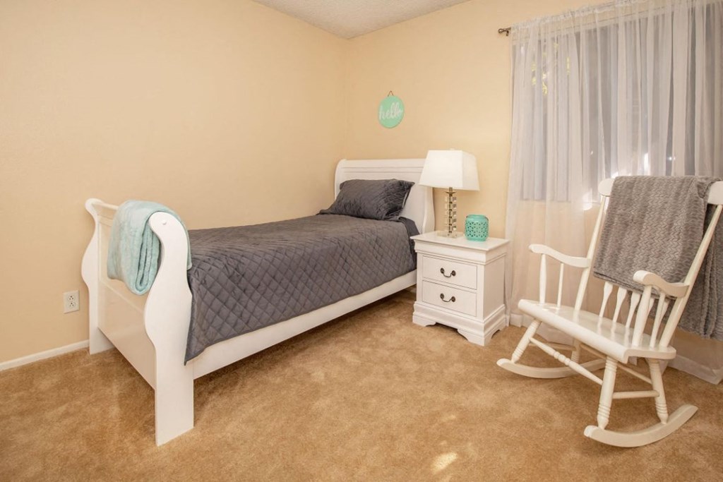 a bedroom with a bed and a rocking chair