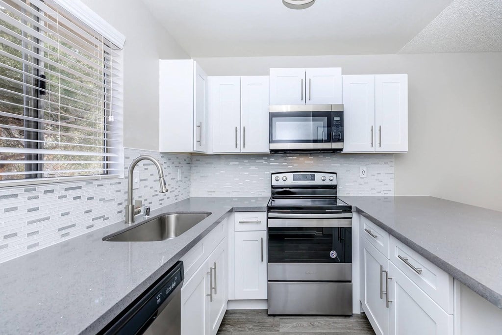 a modern kitchen with white cabinets and stainless steel appliances