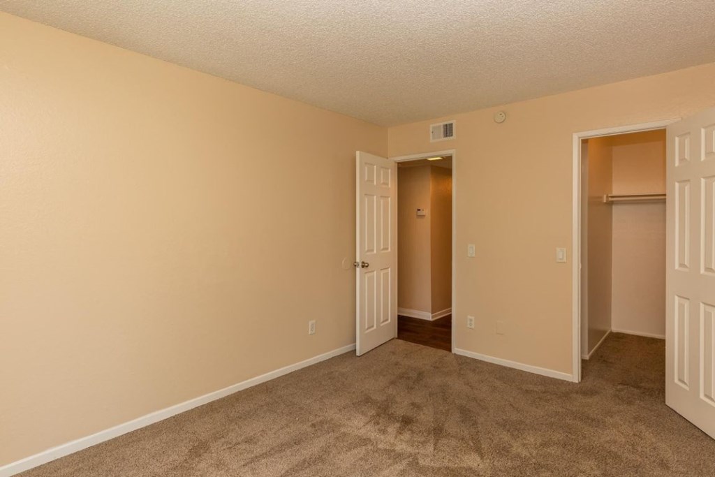 an empty living room with a door open to a closet