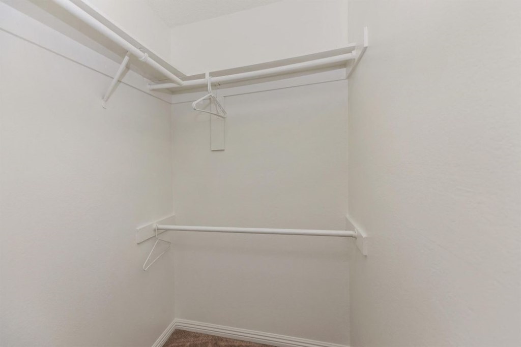 a walk in closet with white walls and a white rack on the wall