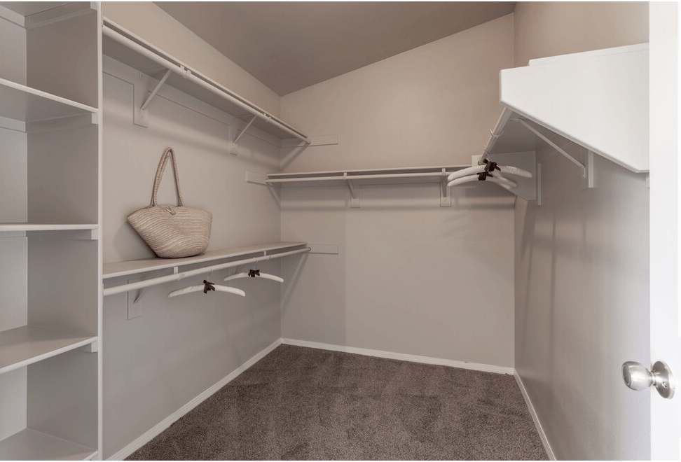 a walk in closet with white shelves and a white closet door