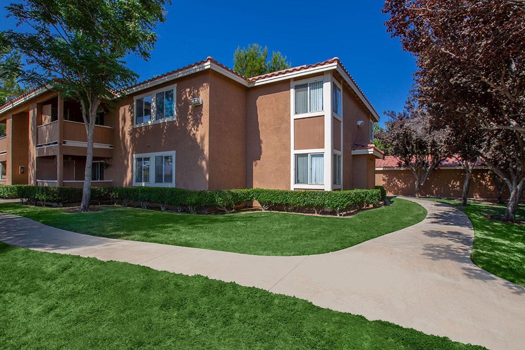 an apartment building with a sidewalk and lawn in front of it