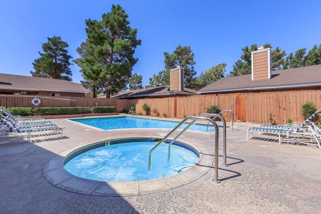 a hot tub in a resort style pool with chairs and a fence