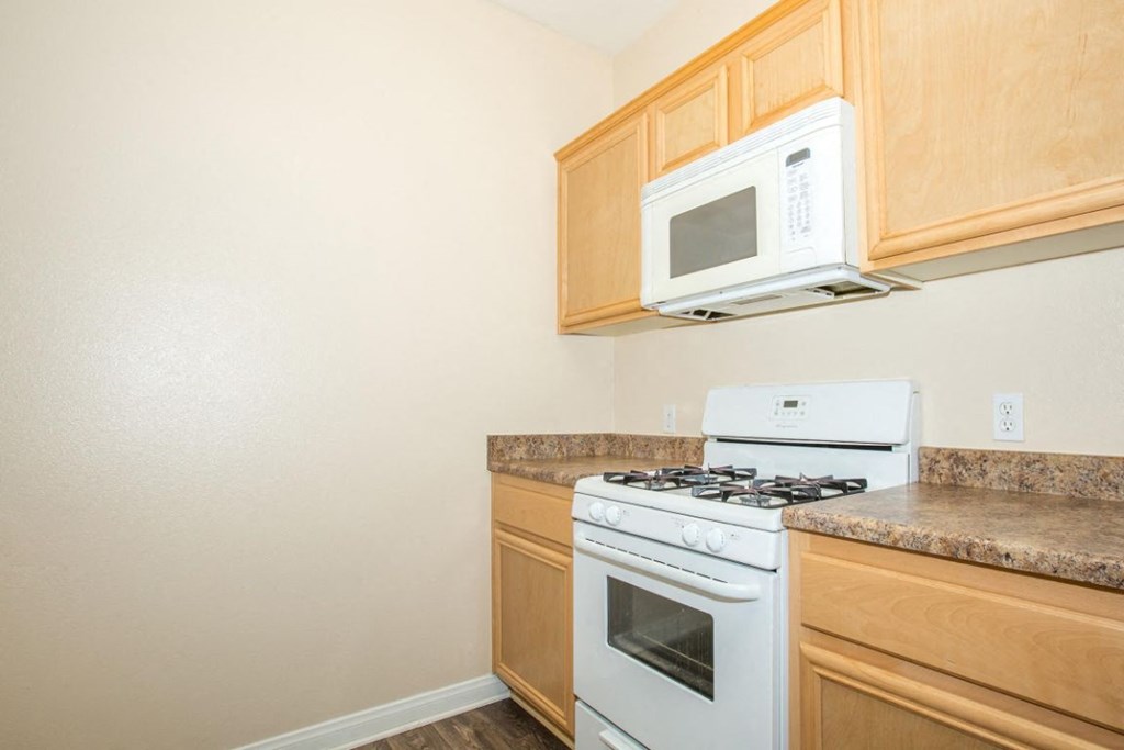 A white stove and microwave in a kitchen with wooden cabinets.