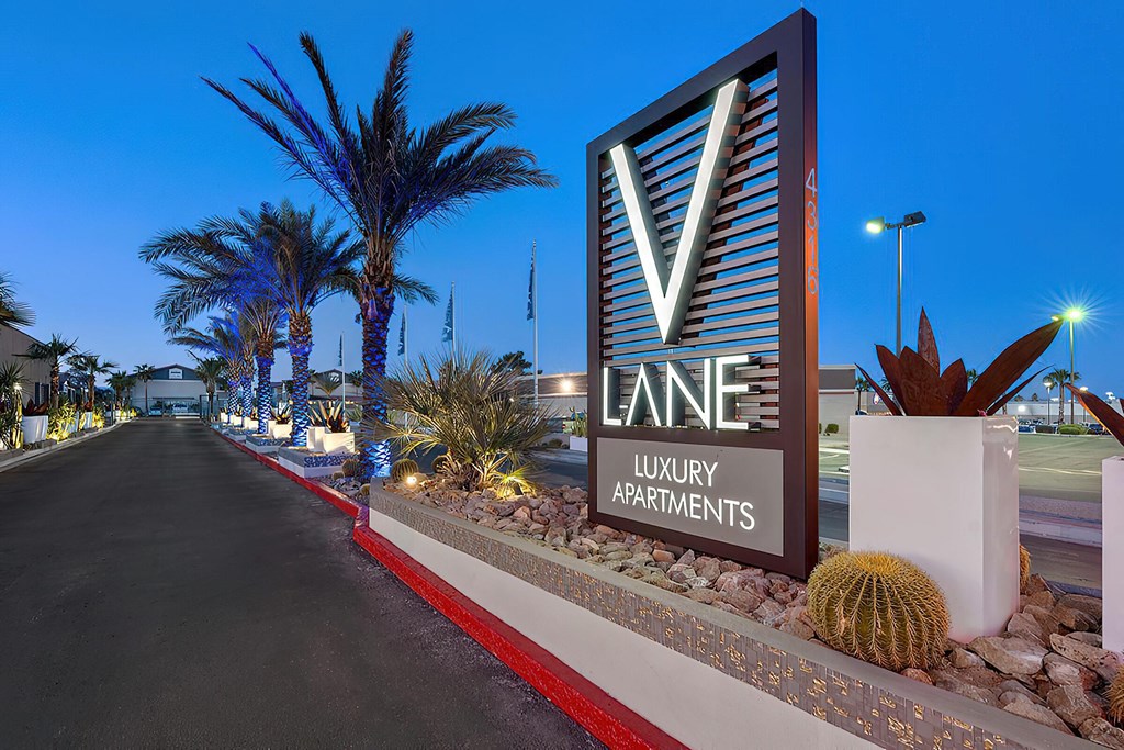 a sign for lane luxury apartments in front of a road and palm trees