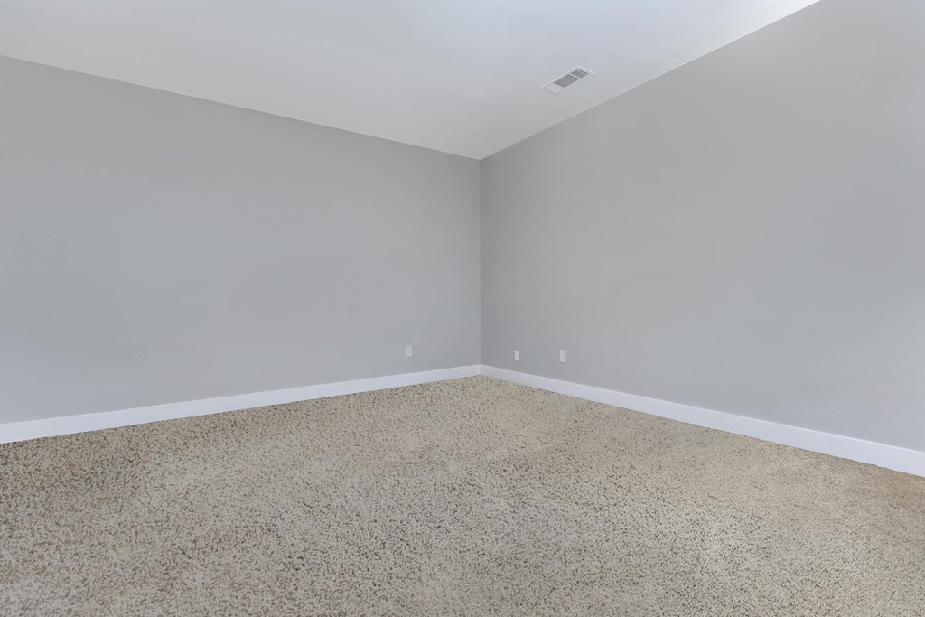 an empty room with a carpeted floor and gray walls