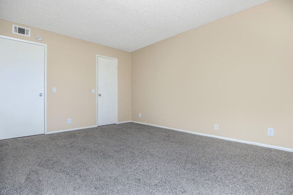 A room with carpeted floor and two doors.