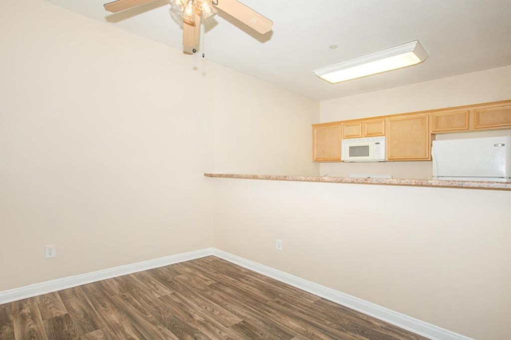 A room with a ceiling fan and a refrigerator in the corner.