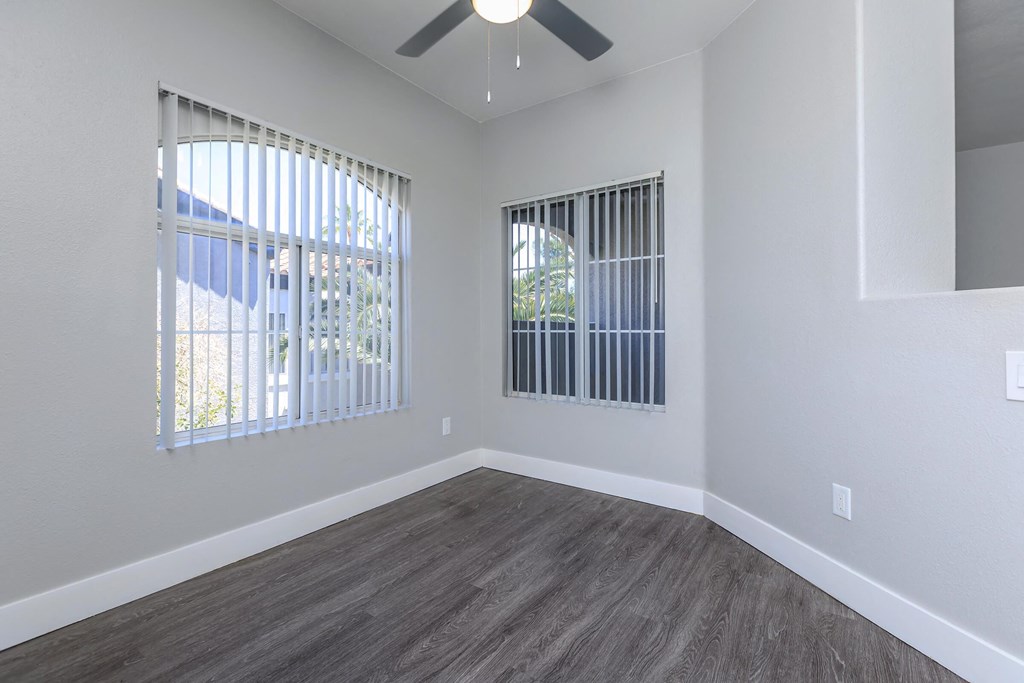 an empty living room with windows and a ceiling fan