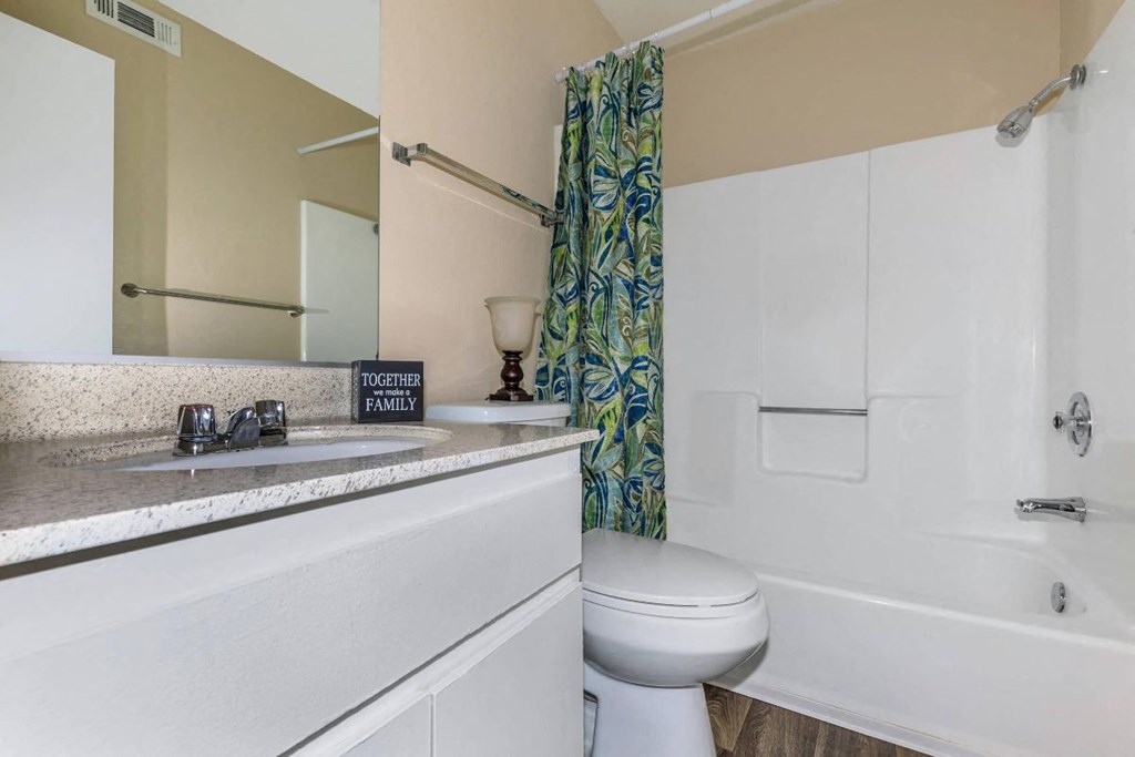 A white toilet sits next to a bathtub in a bathroom.