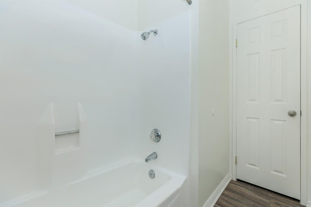 a white bathroom with a tub and a door