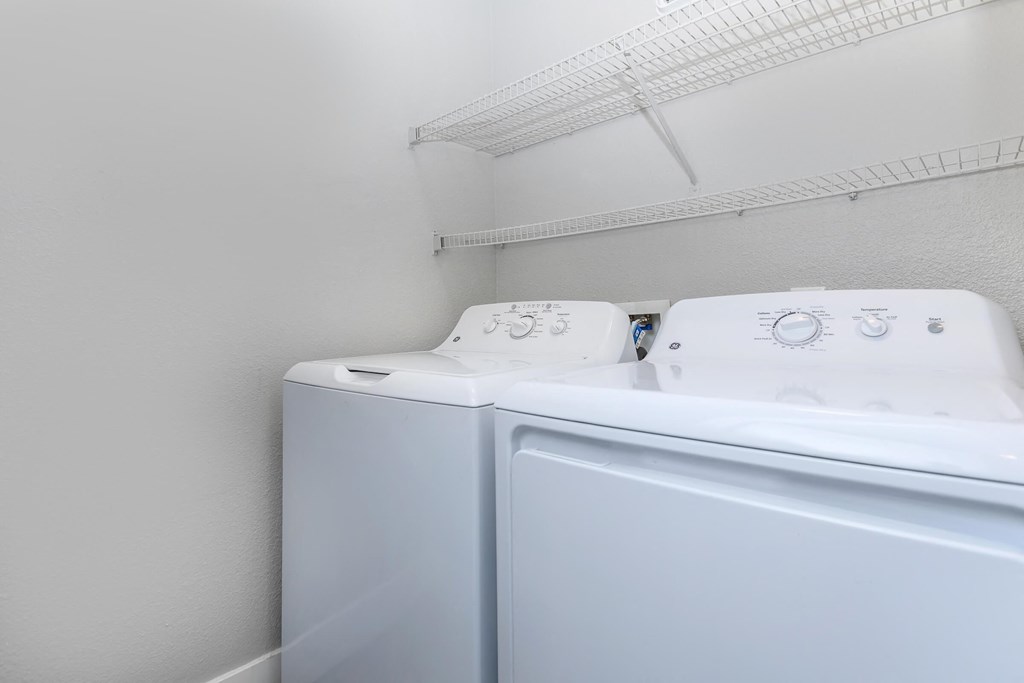 the laundry room has a washer and dryer and a shelf over the top