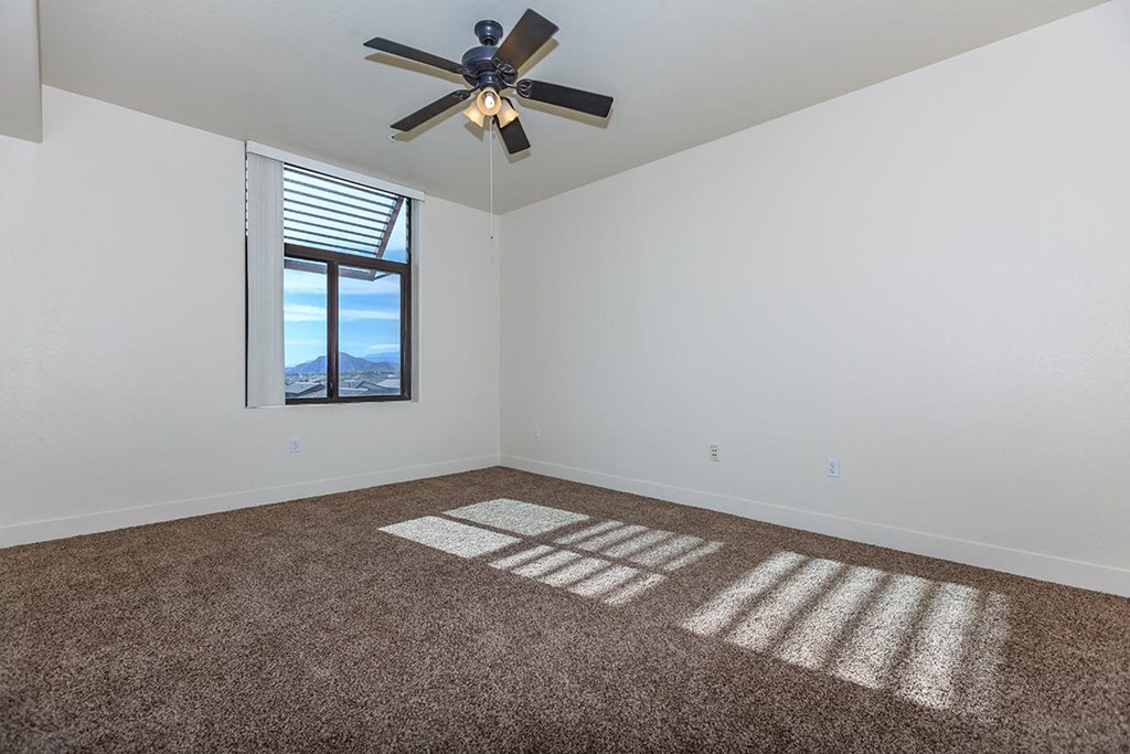 an empty living room with a ceiling fan and a window