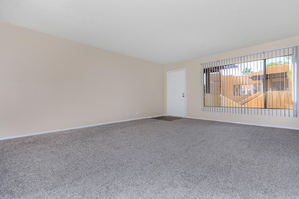 Empty room with a carpeted floor and a window with bars.