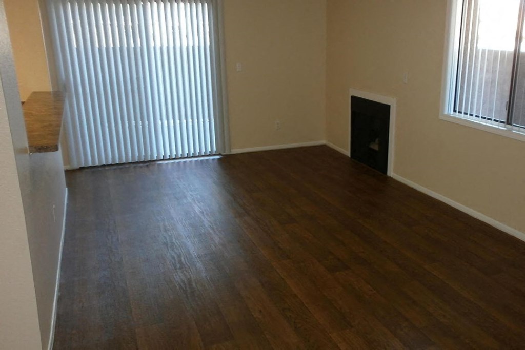 an empty living room with wood floors and a fireplace