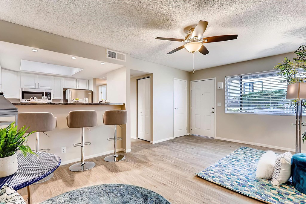 a living room with a kitchen and a ceiling fan