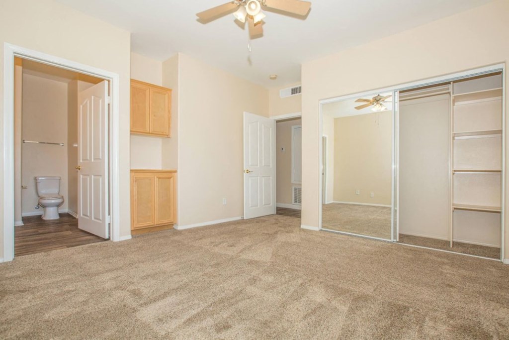 A room with a carpeted floor and a ceiling fan.
