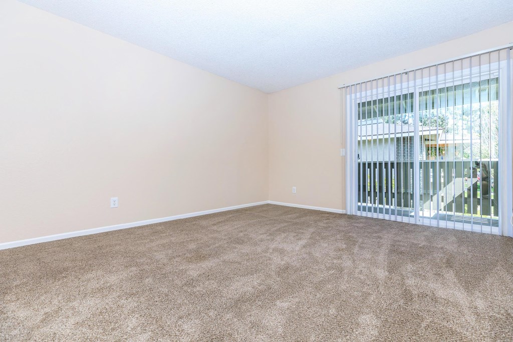 an empty living room with a large window and carpet