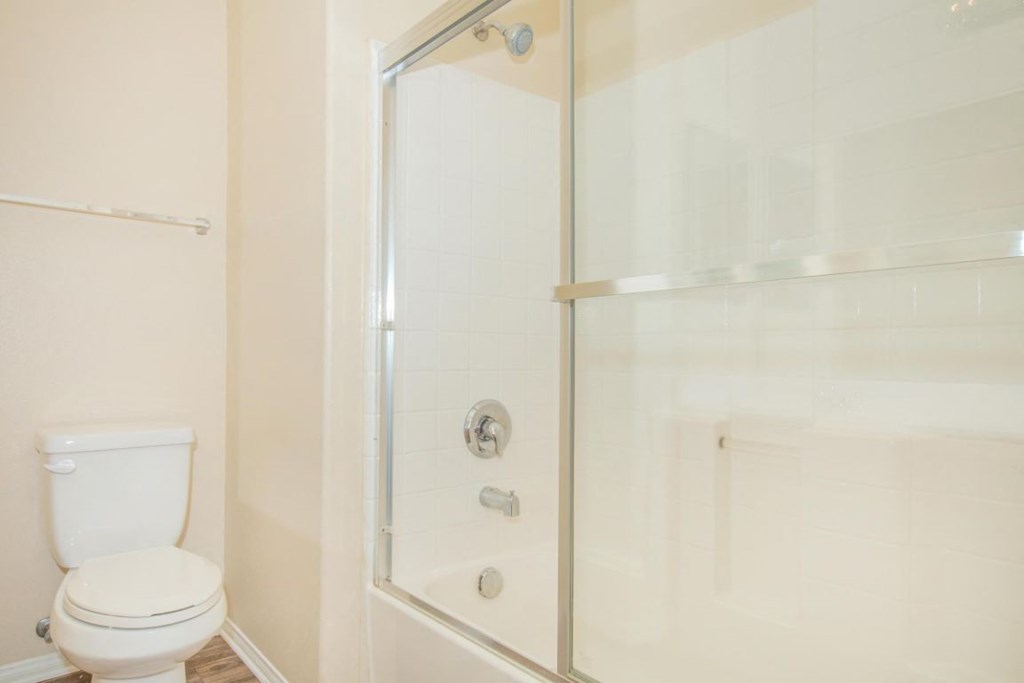 A white toilet sits next to a glass shower door.