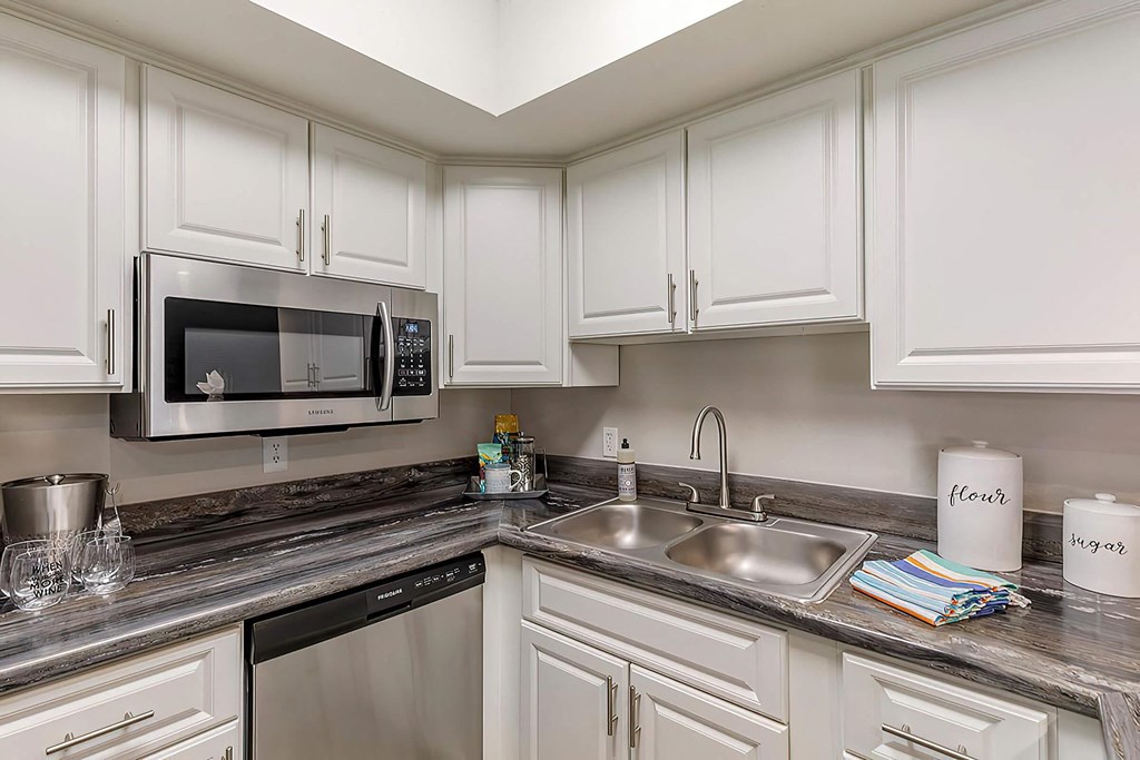 a kitchen with white cabinets and a sink and a microwave