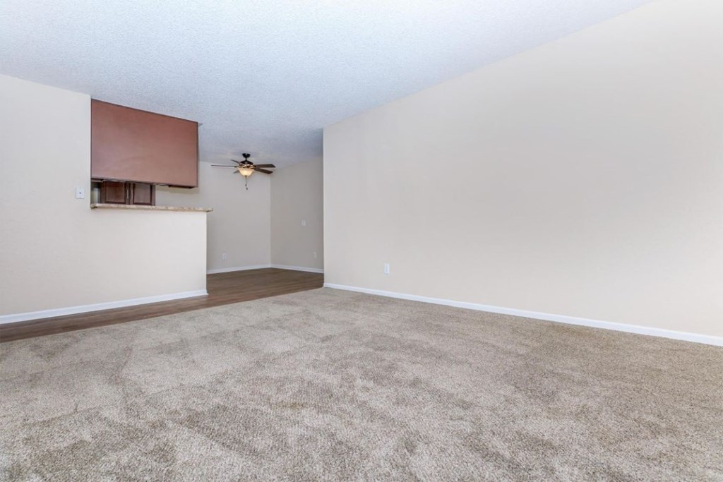 an empty living room with a ceiling fan