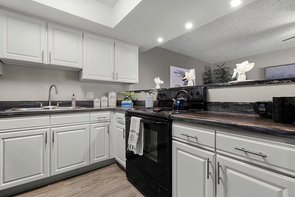 a kitchen with white cabinets and black appliances