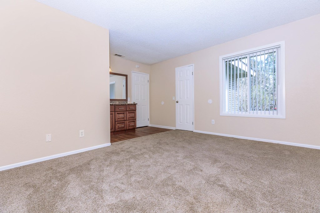 an empty living room with a large window and carpet