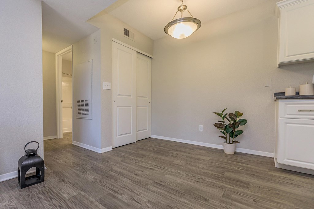 the spacious living room with white walls and wood flooring