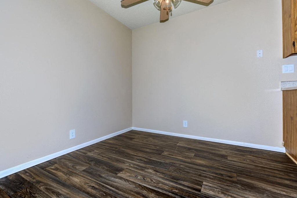 A room with a ceiling fan and wooden flooring.