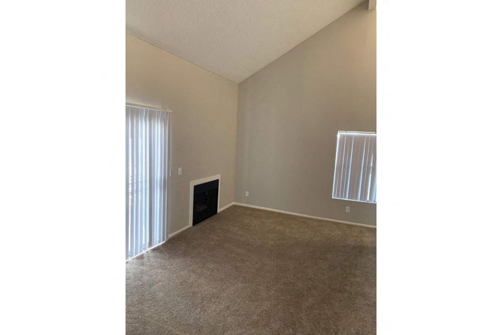 an empty living room with a window and a fireplace