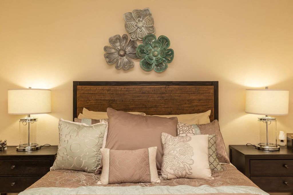 a bedroom with a bed with pillows and flowers on the wall