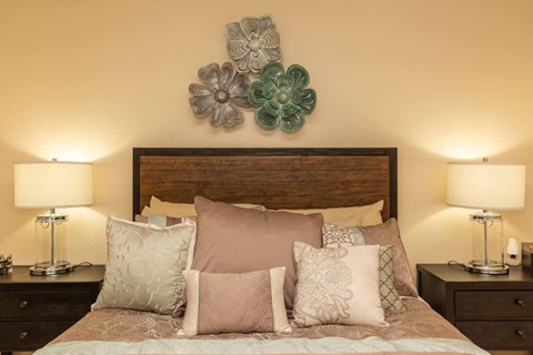 a bedroom with a bed with pillows and flowers on the wall