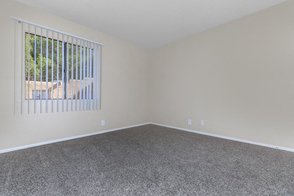 A room with a window covered by vertical blinds.