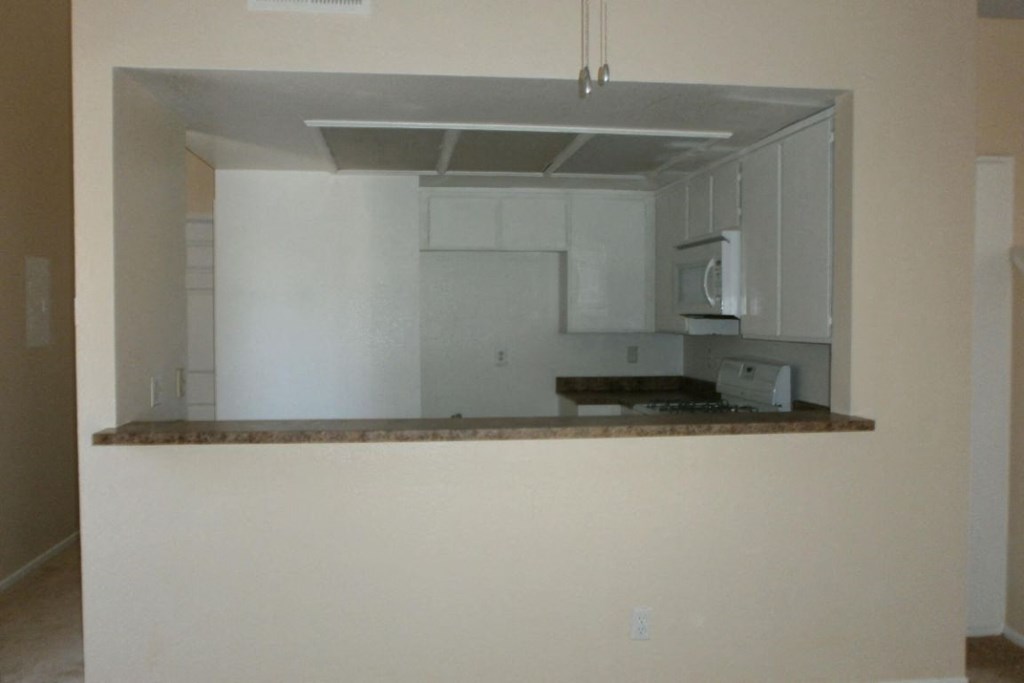 an empty kitchen with white cabinets and a counter top