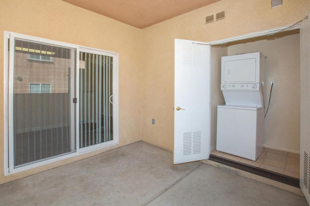 A room with a white fridge and a sliding glass door.